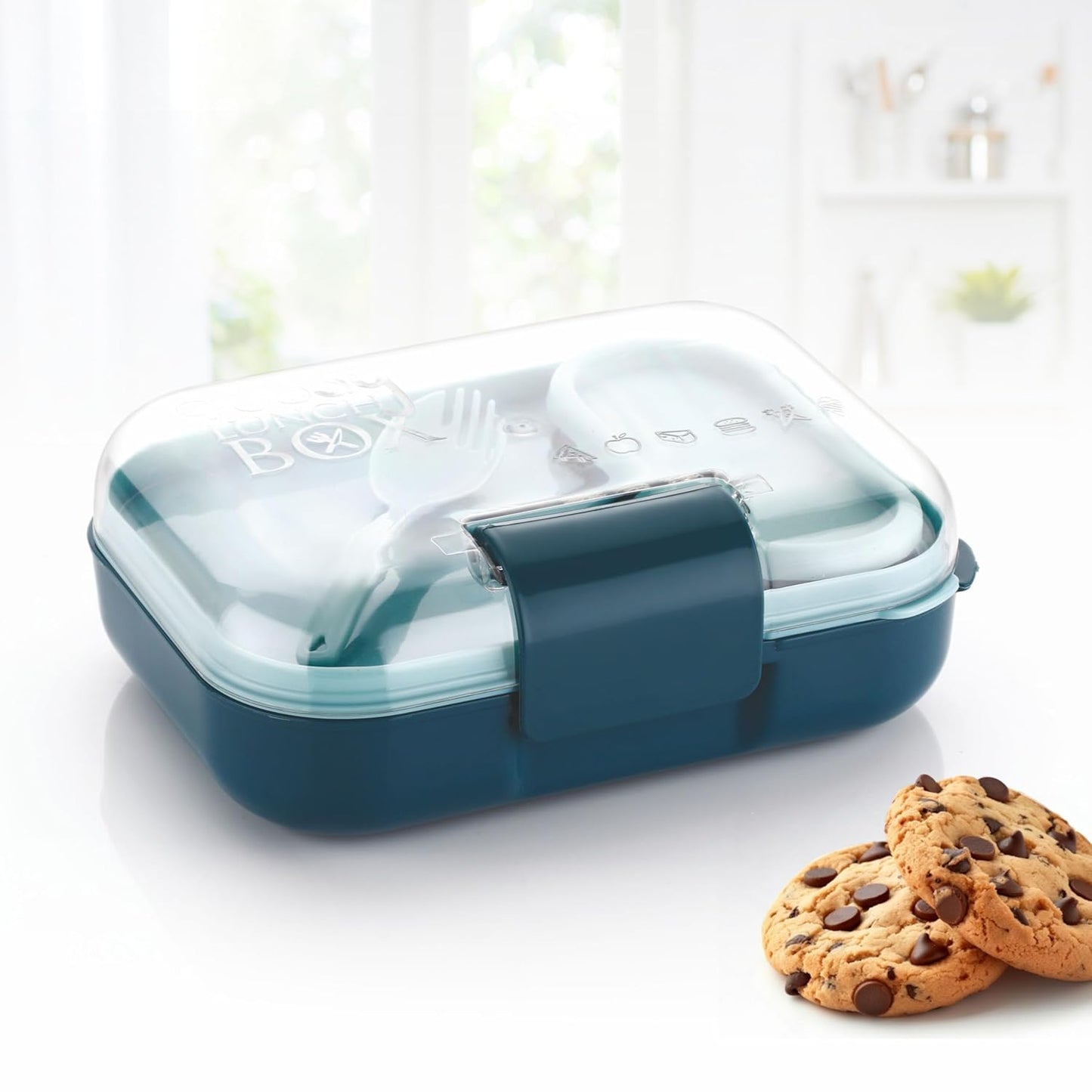 Teal plastic lunch box with clear lid and spoon beside cookies