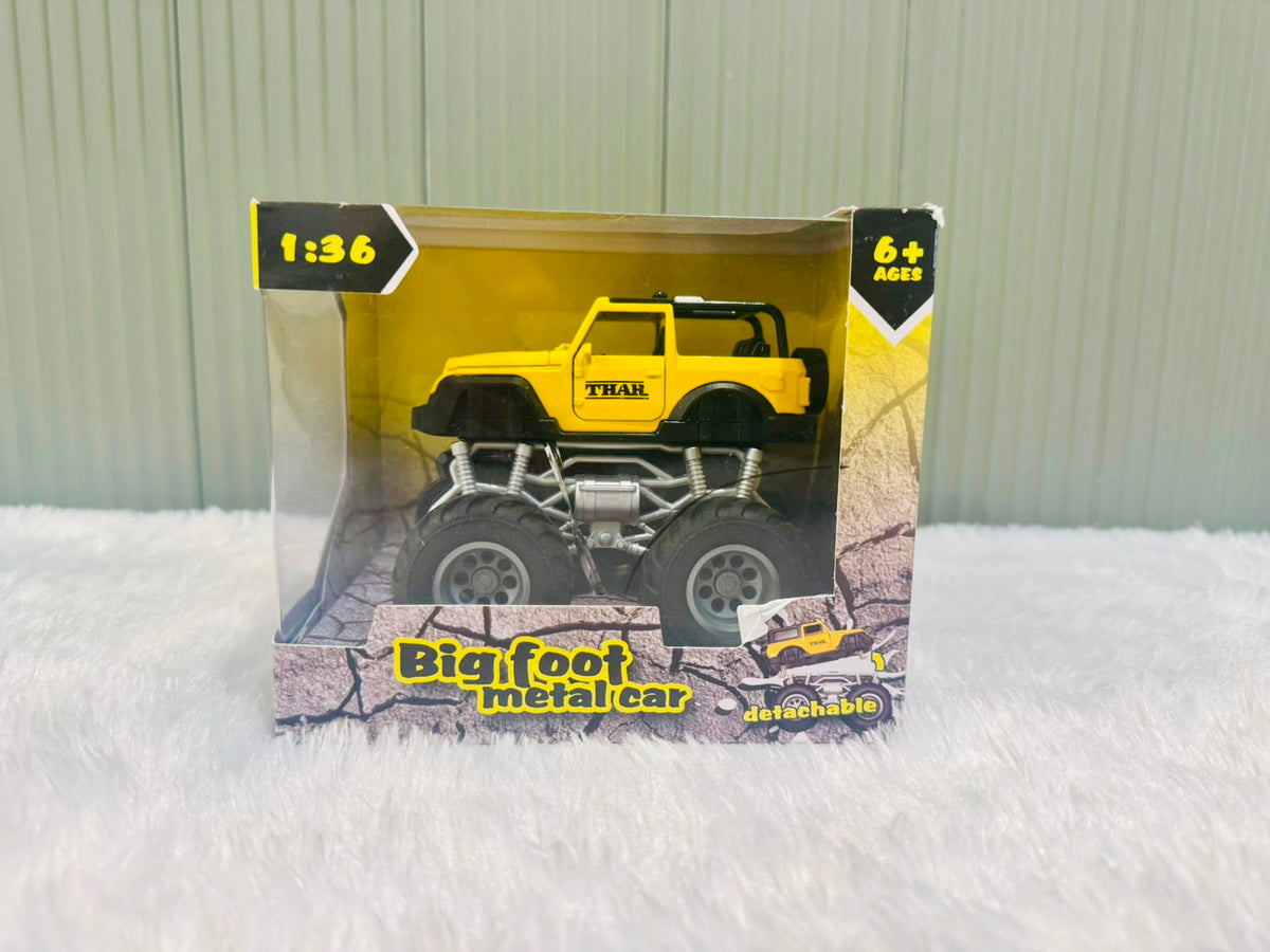 Yellow die cast off road toy car with oversized wheels in its box