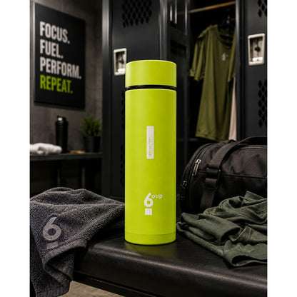 Green 6oup glass bottle on a gym bench in a locker room setting