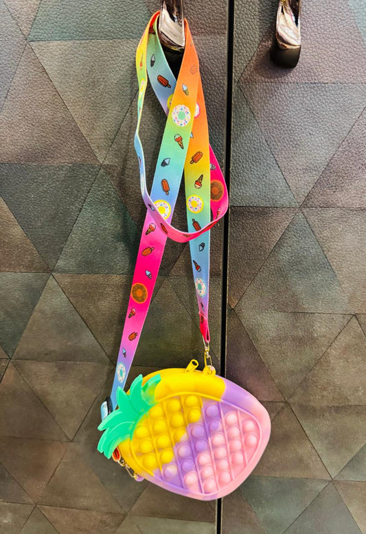 Rainbow pineapple pop it sling bag hanging from a strap on a door