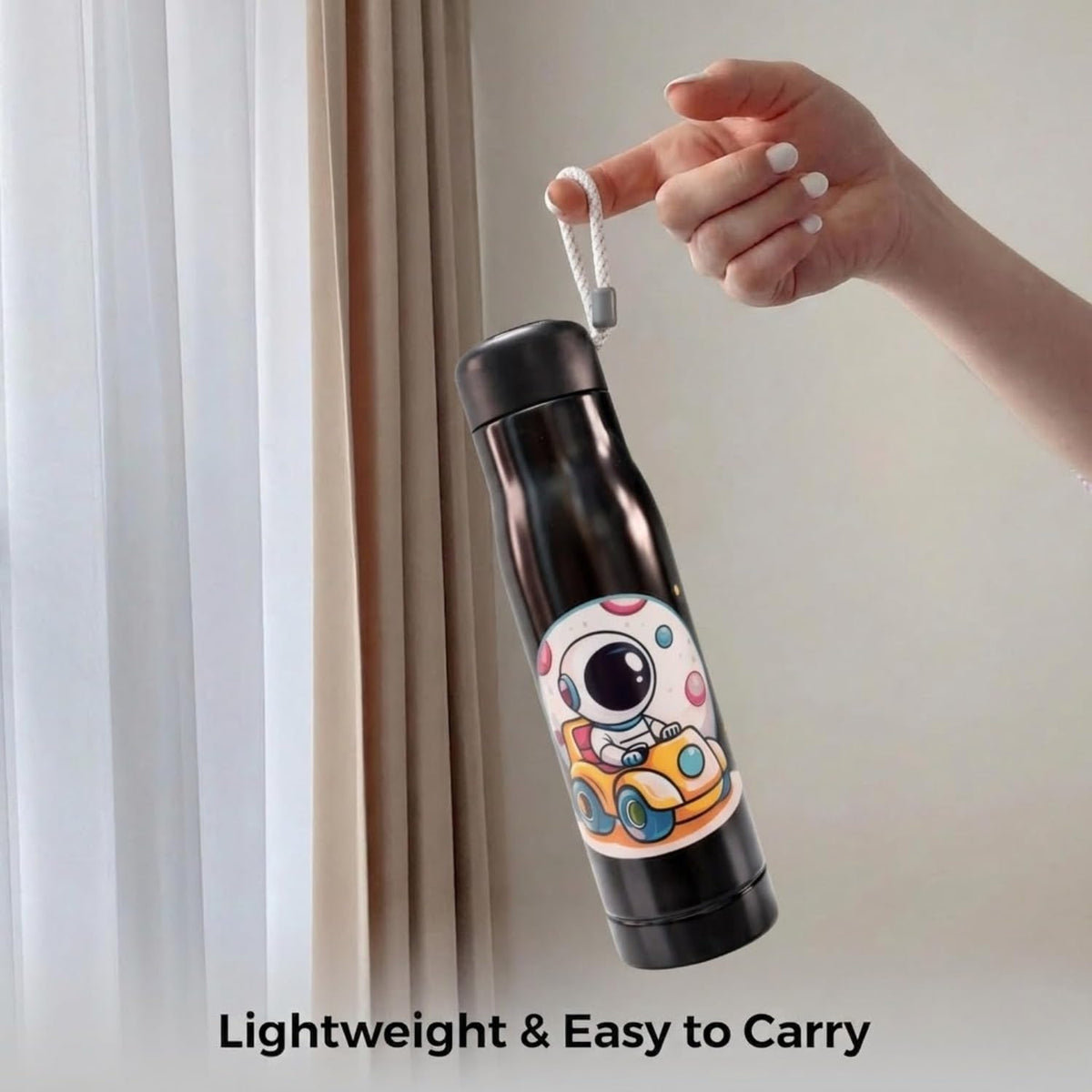 Hand lifting the black 550ml astronaut print bottle by its rope strap