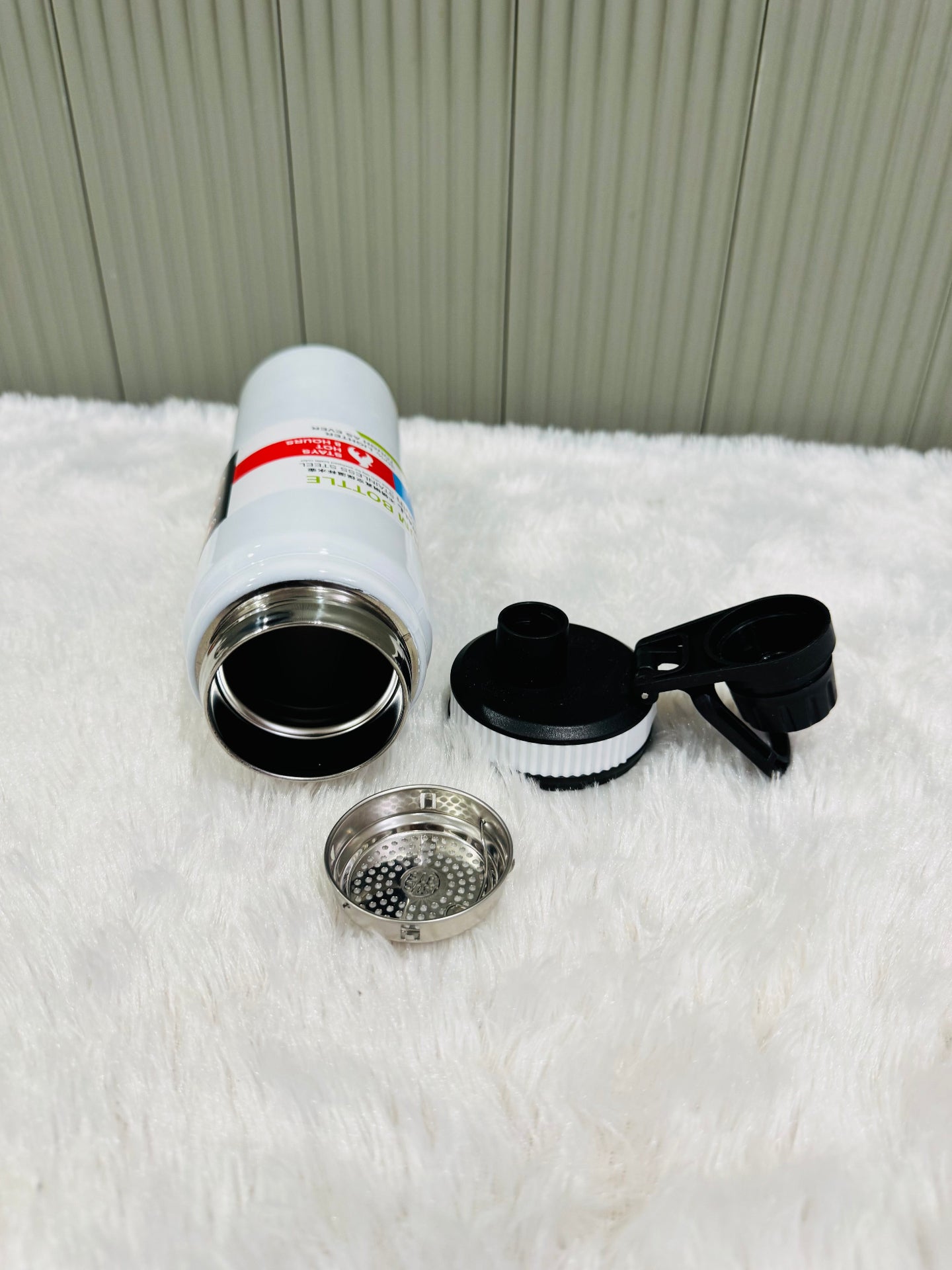 White 800ml bottle lying down with lid and steel strainer alongside