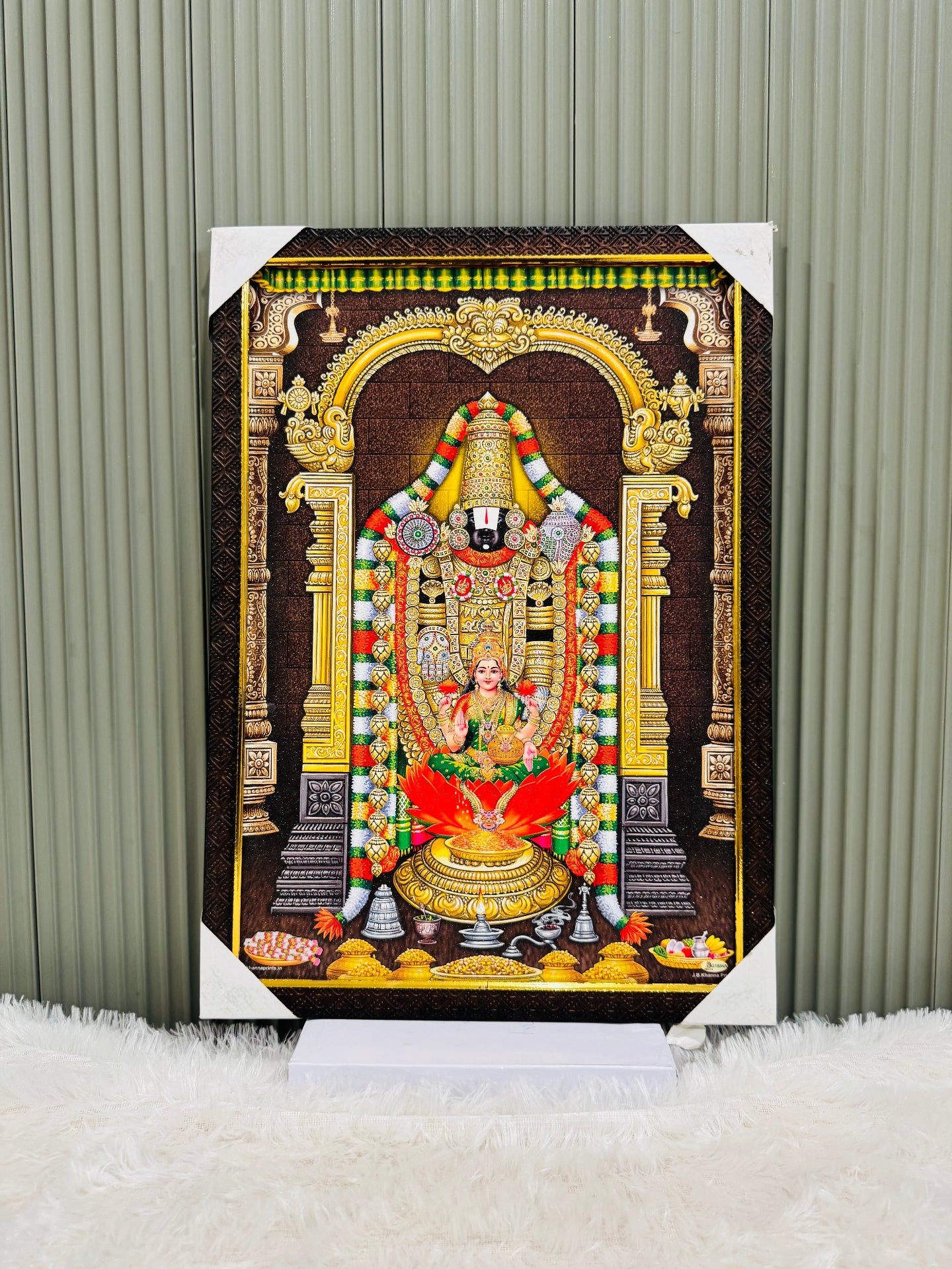 Golden framed Tirupati Balaji wall painting on a stand against a panel wall