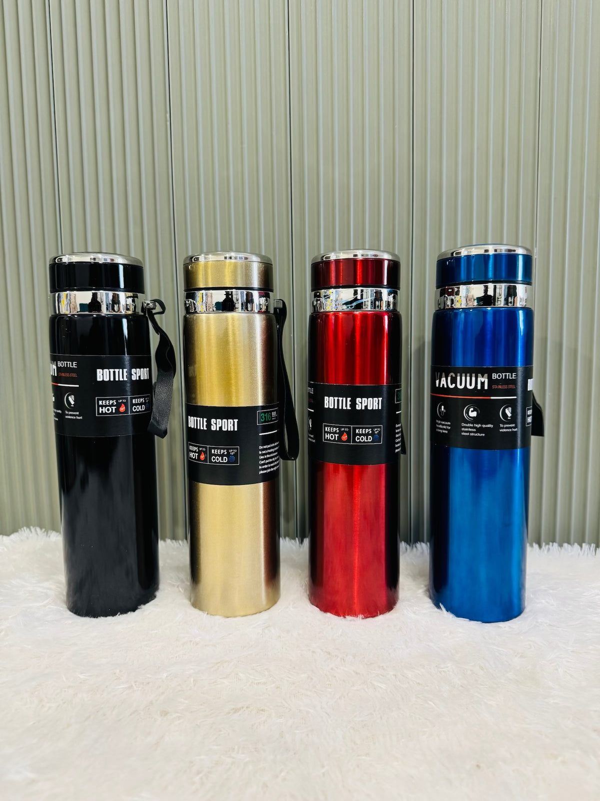 Four 1000ml sport flasks in black, gold, red and blue on a rug