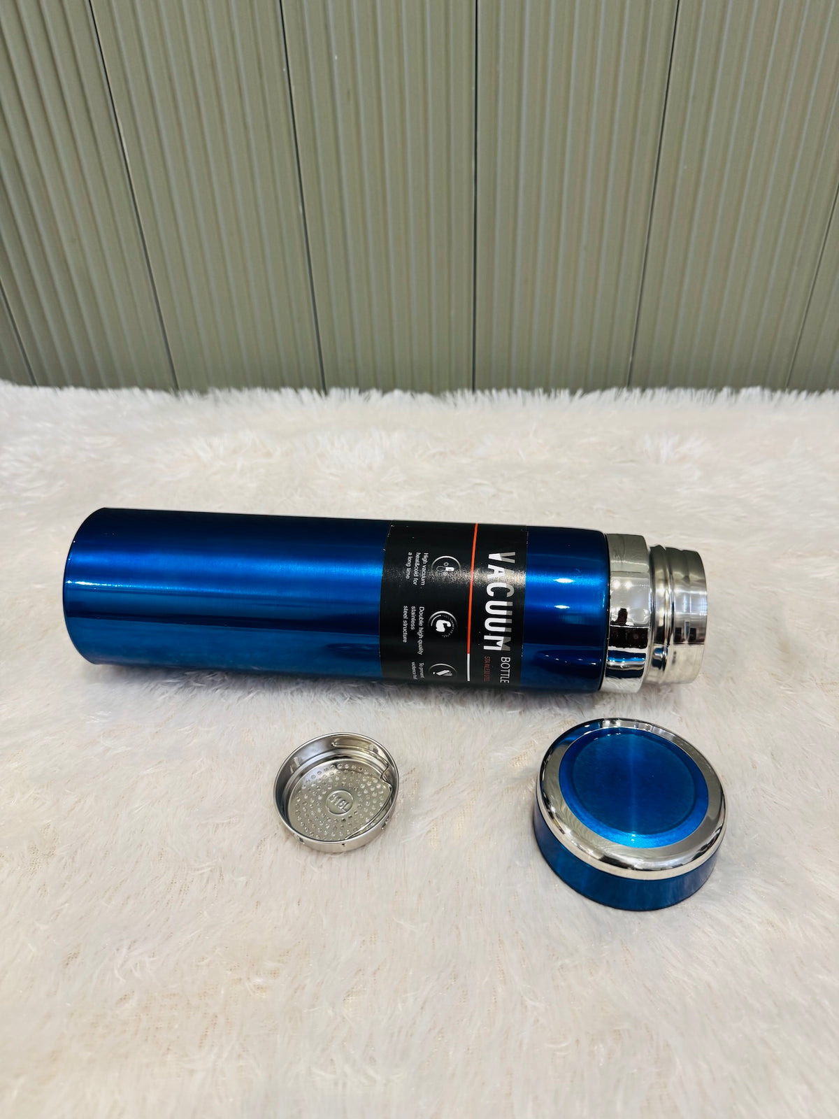 Blue 1000ml flask on its side beside the strainer and blue cup lid