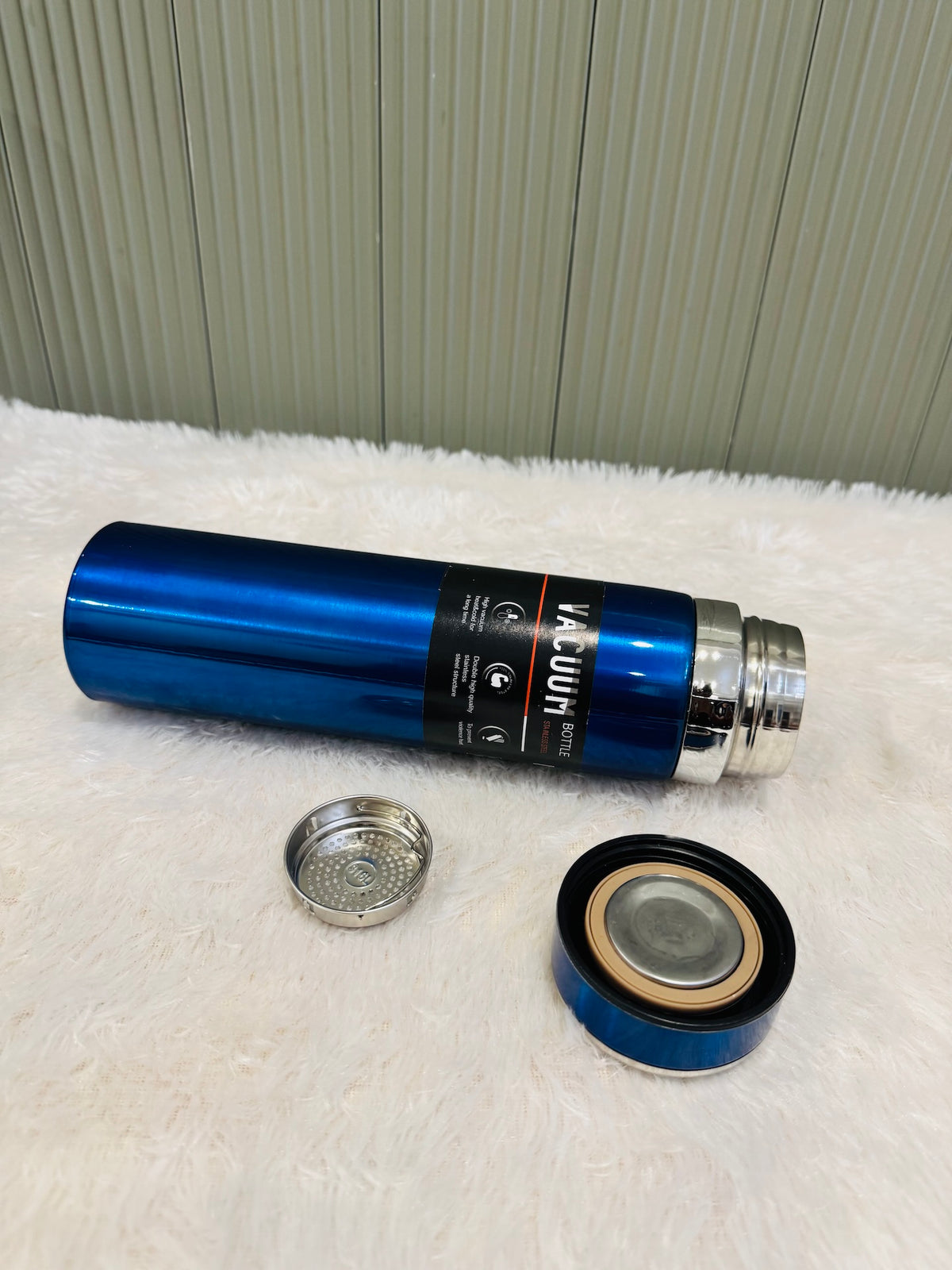 Blue 1000ml flask lying down with its cup lid and steel strainer