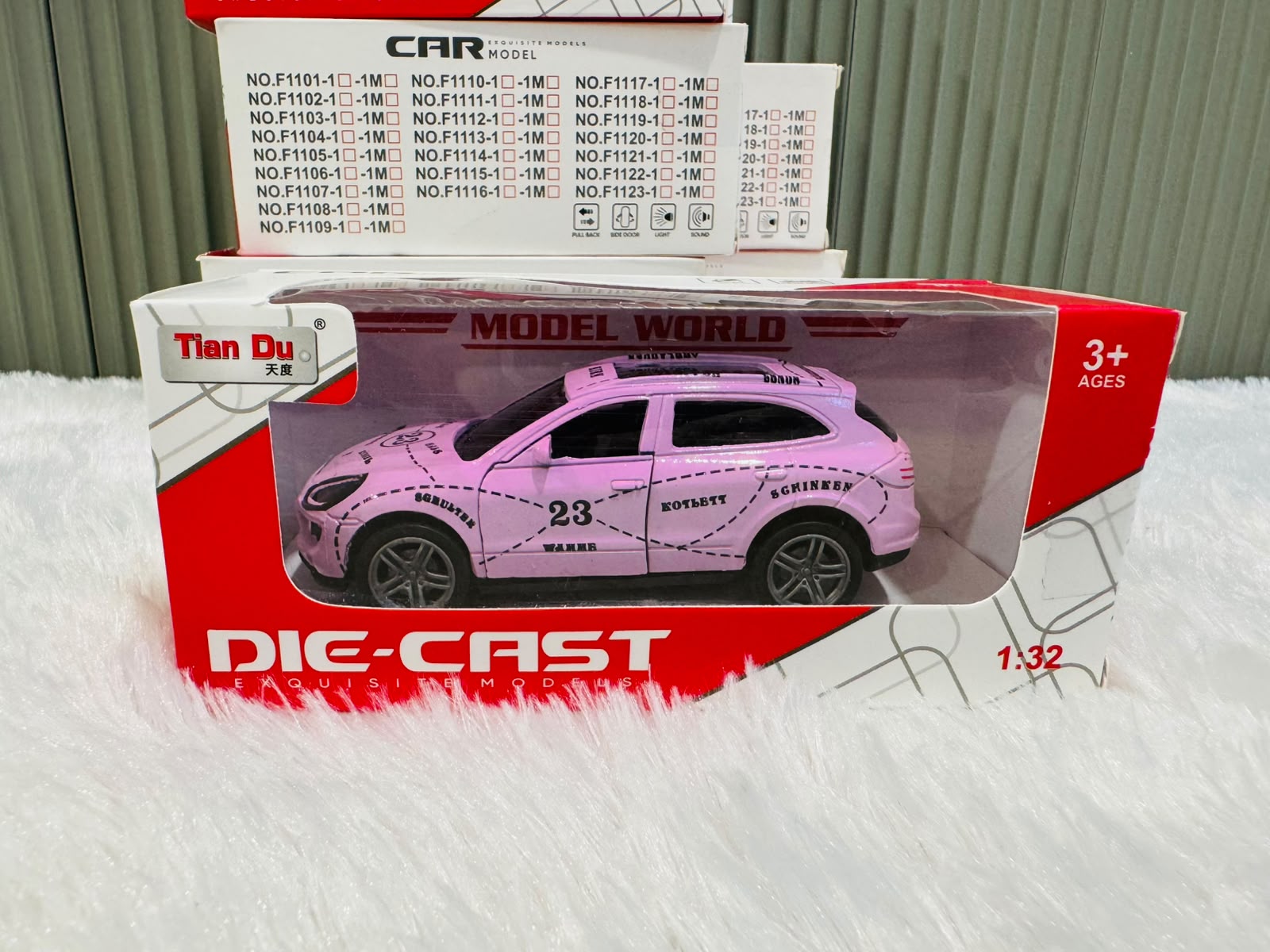 Pink boxed 1:32 die cast racing toy car with model list behind