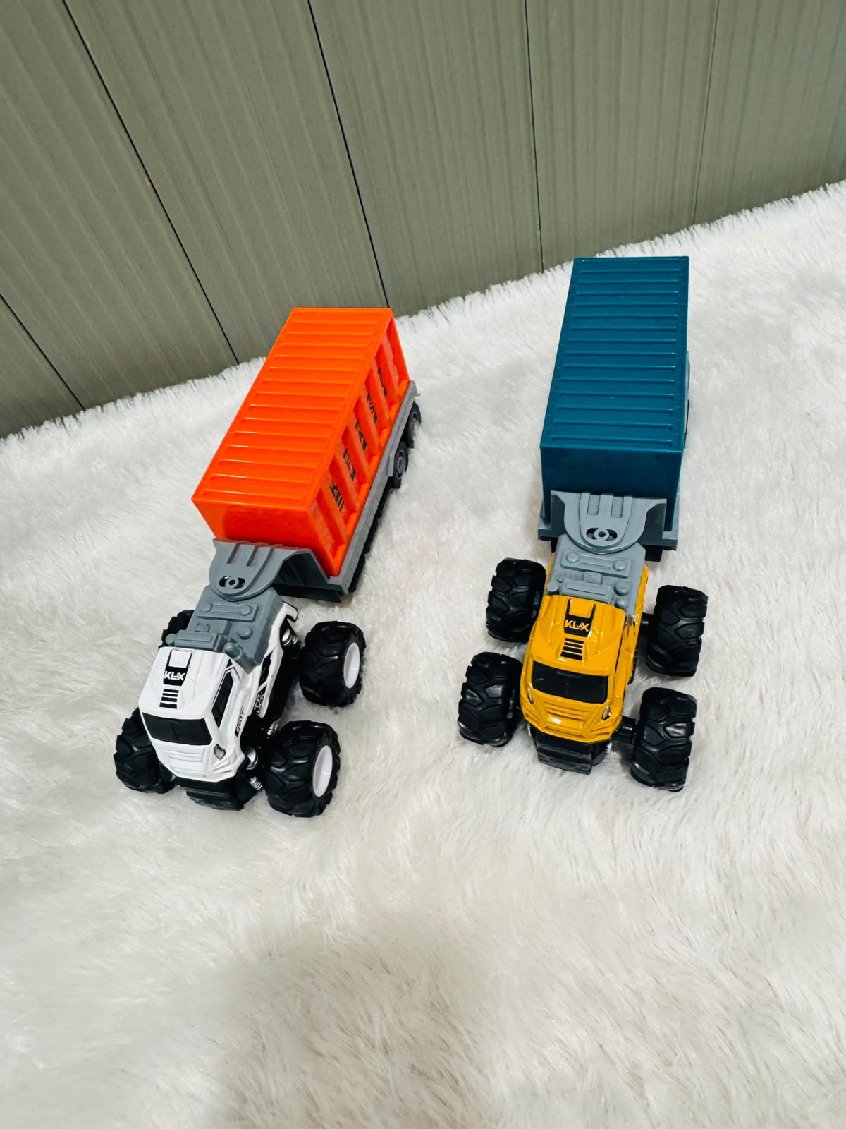 Red and blue container truck toys with oversized wheels on a rug