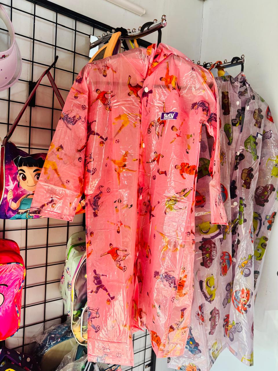 Pink cartoon print kids raincoats hanging together on a display grid