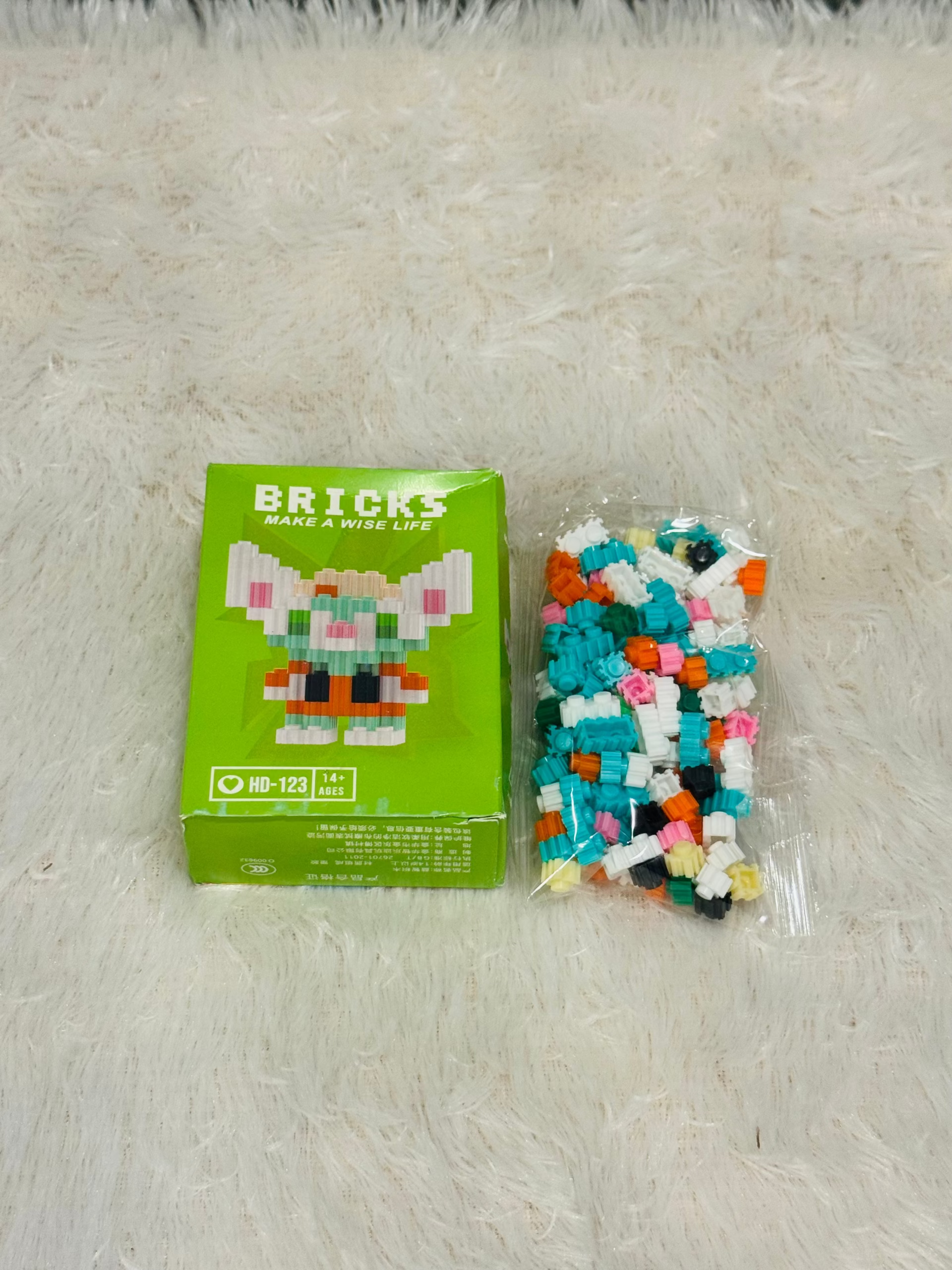 Green bricks block box beside a bag of loose teal building pieces