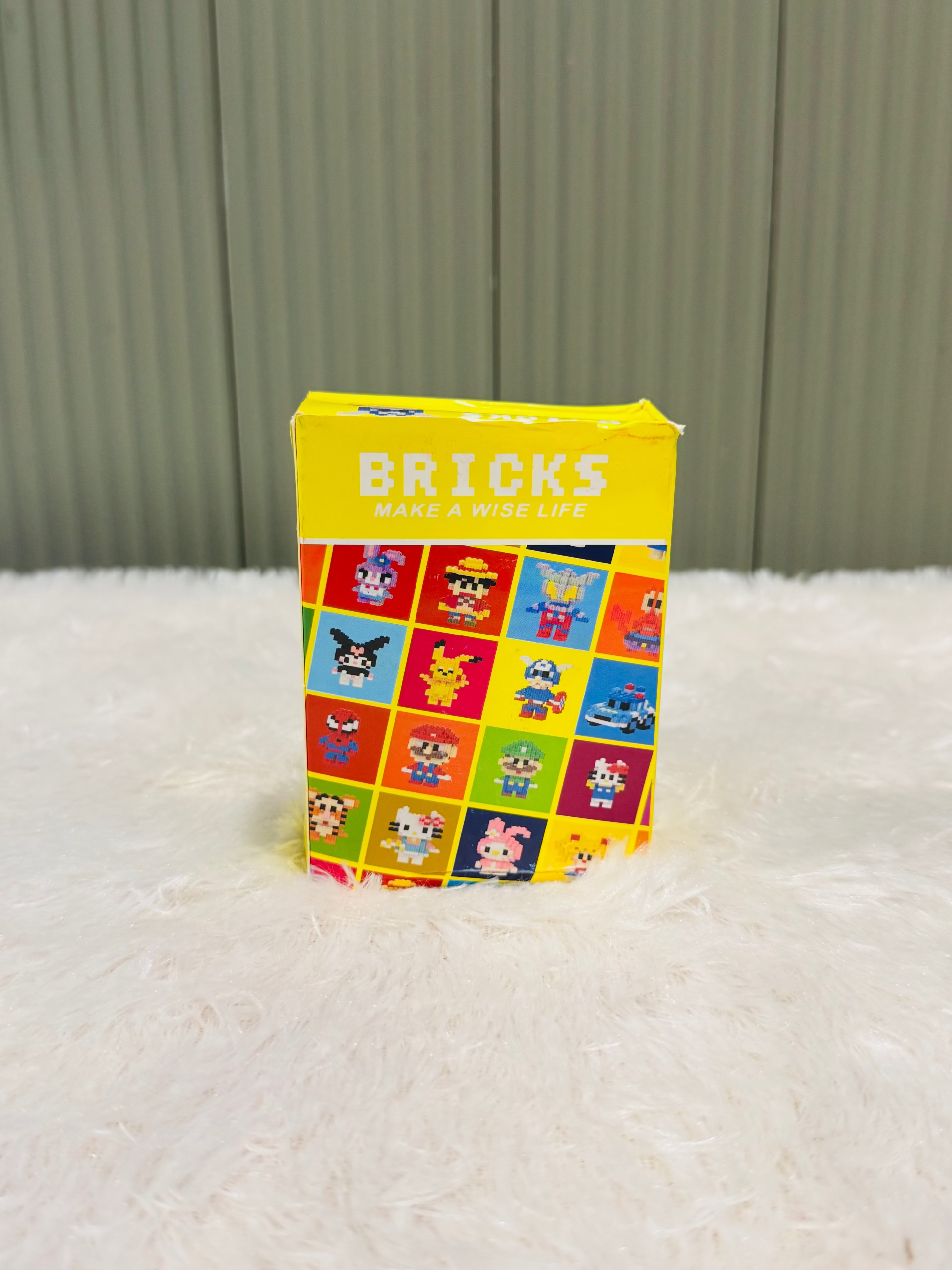 Yellow bricks block box with a colourful character grid printed on the side