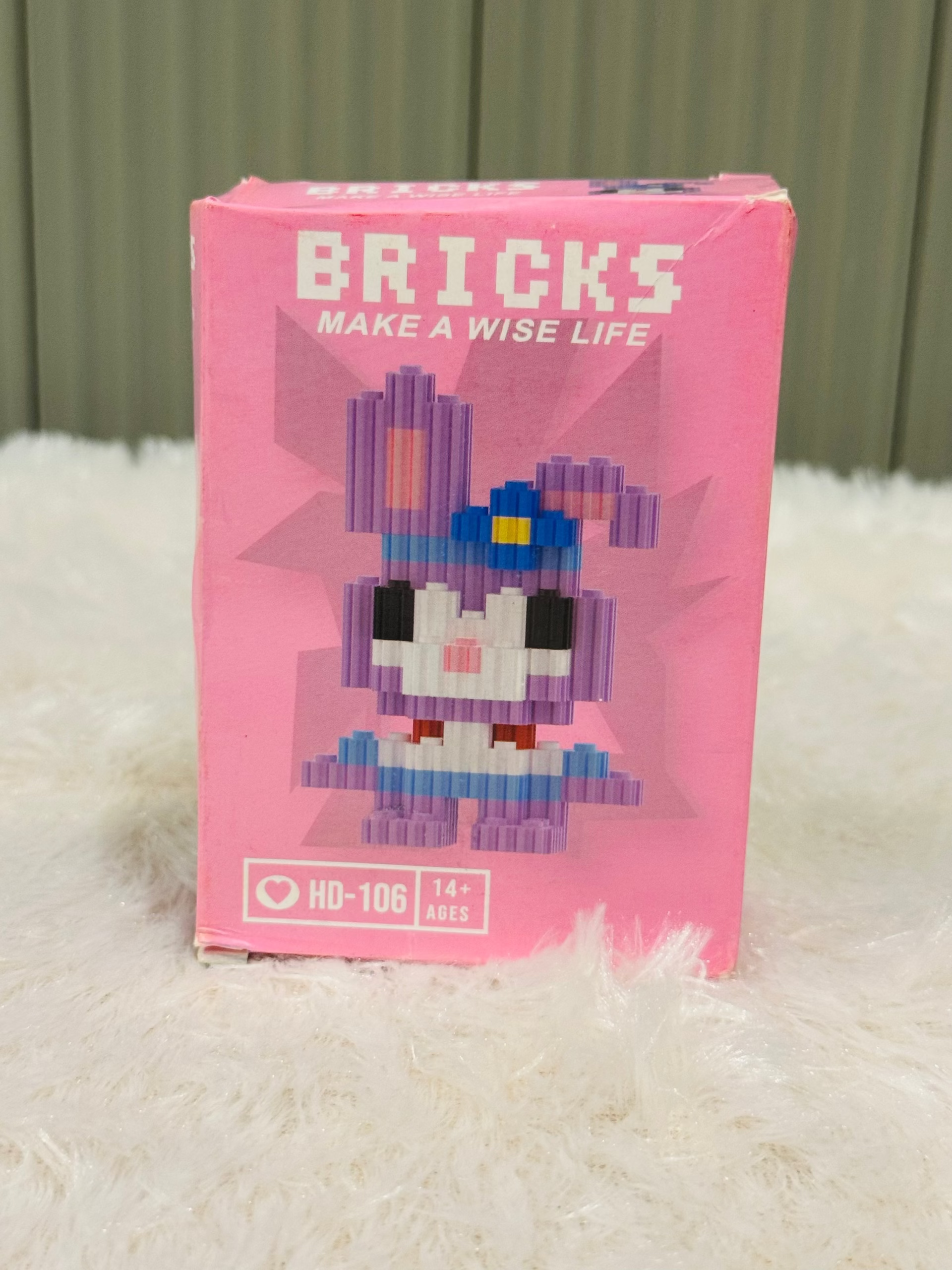 Pink bricks block box showing a blue-hatted mini figure on the front