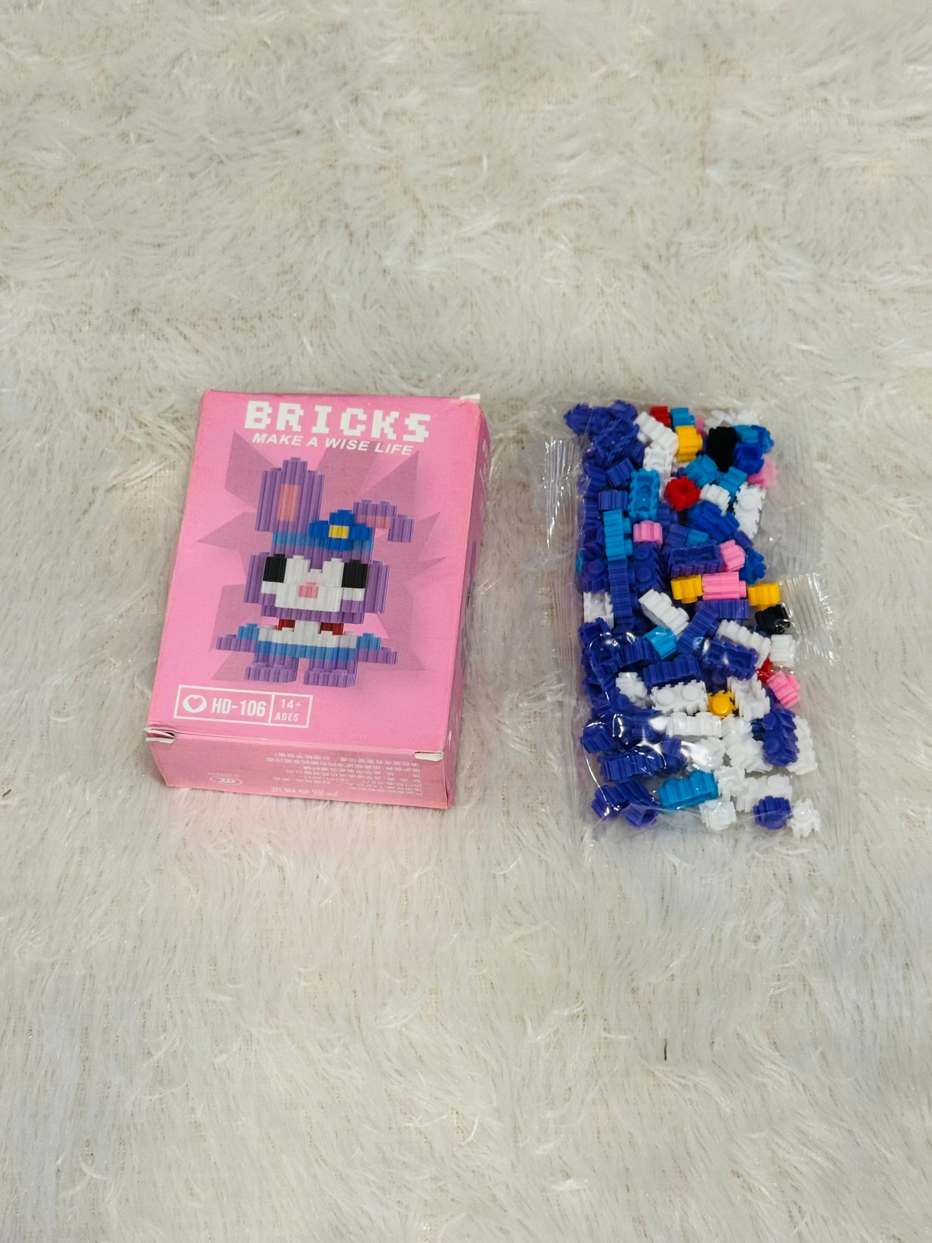 Pink bricks block box beside a bag of blue and white building pieces