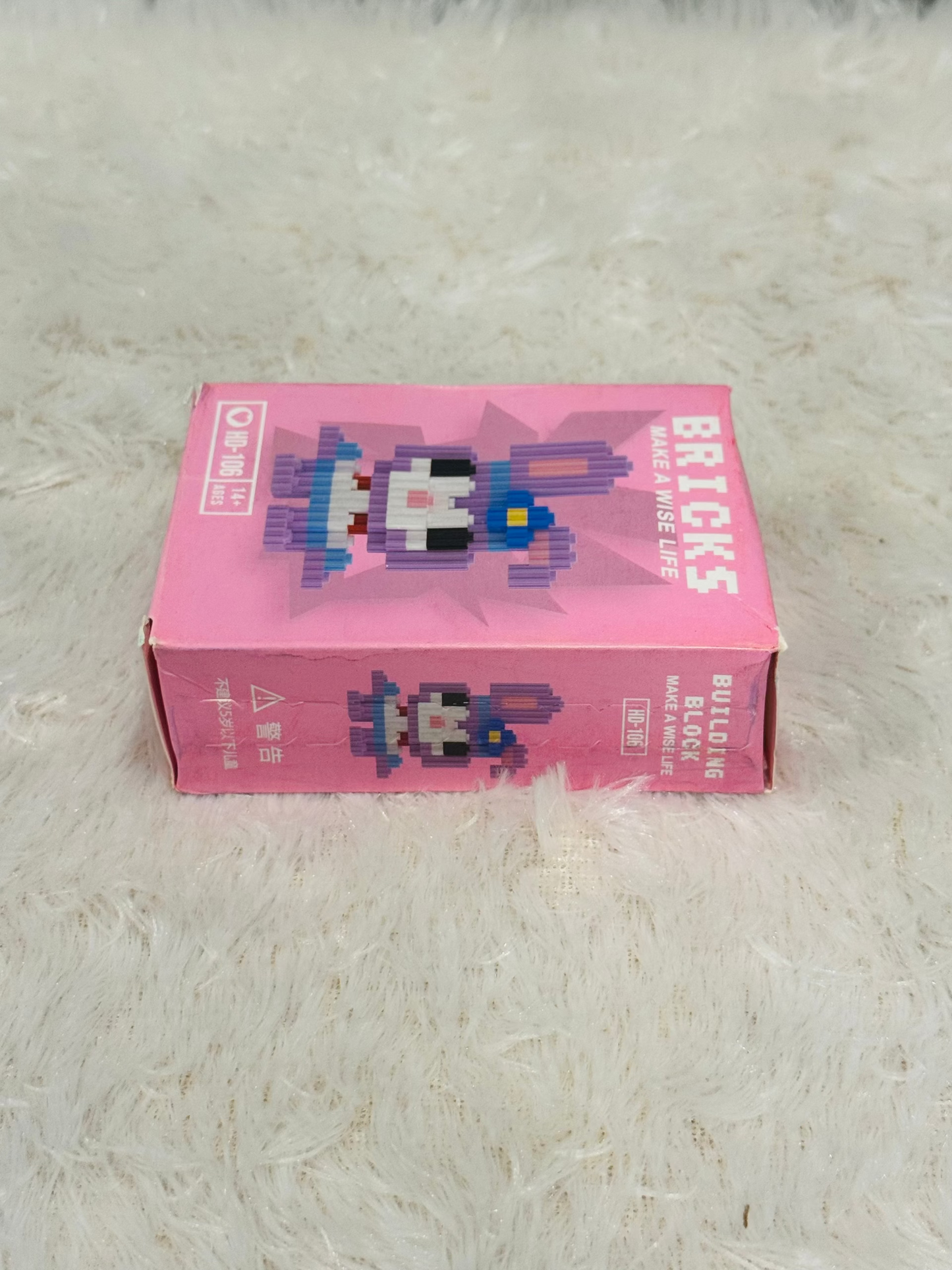 Pink bricks block box photographed on its side on a soft rug